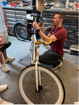 A man working on a bicycle while students stand around him