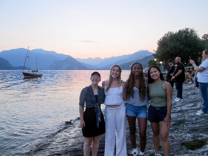 Ella Tingley and three classmates standing in front of a large lake at sunset with mountains in the distance