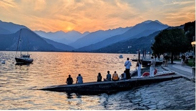 Students sitting on the pier while watching the sunset over a large lake and mountains