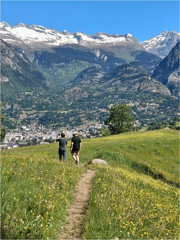 Two students walking through a grassy field next to mountains