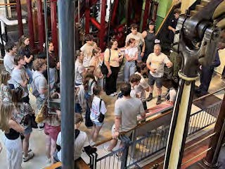 Students listening to their leading faculty talk about a machine in the London Museum of Water and Steam