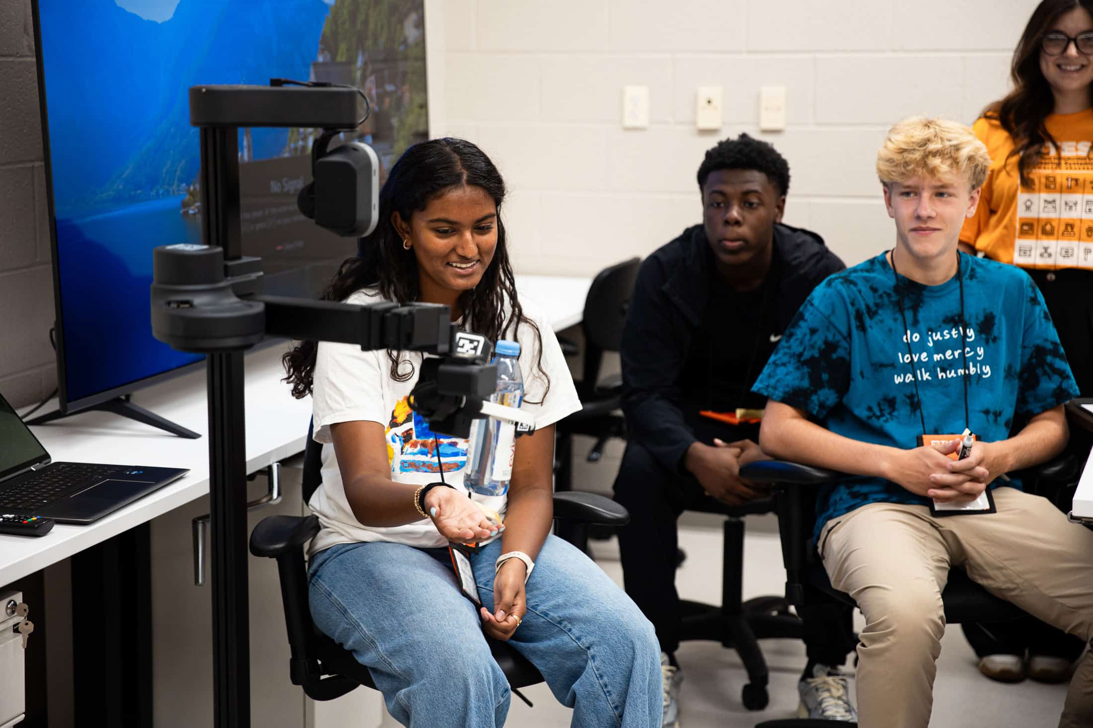 High school seniors observing a mechanical claw holding a water bottle
