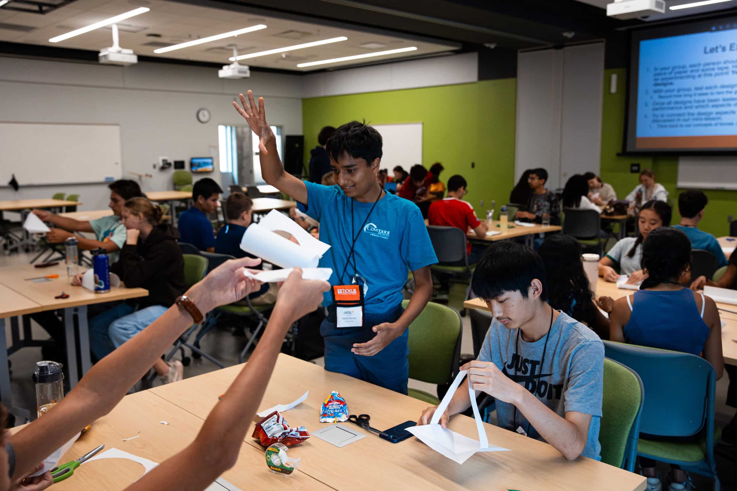 A high schooler dropping a paper airplane onto a table