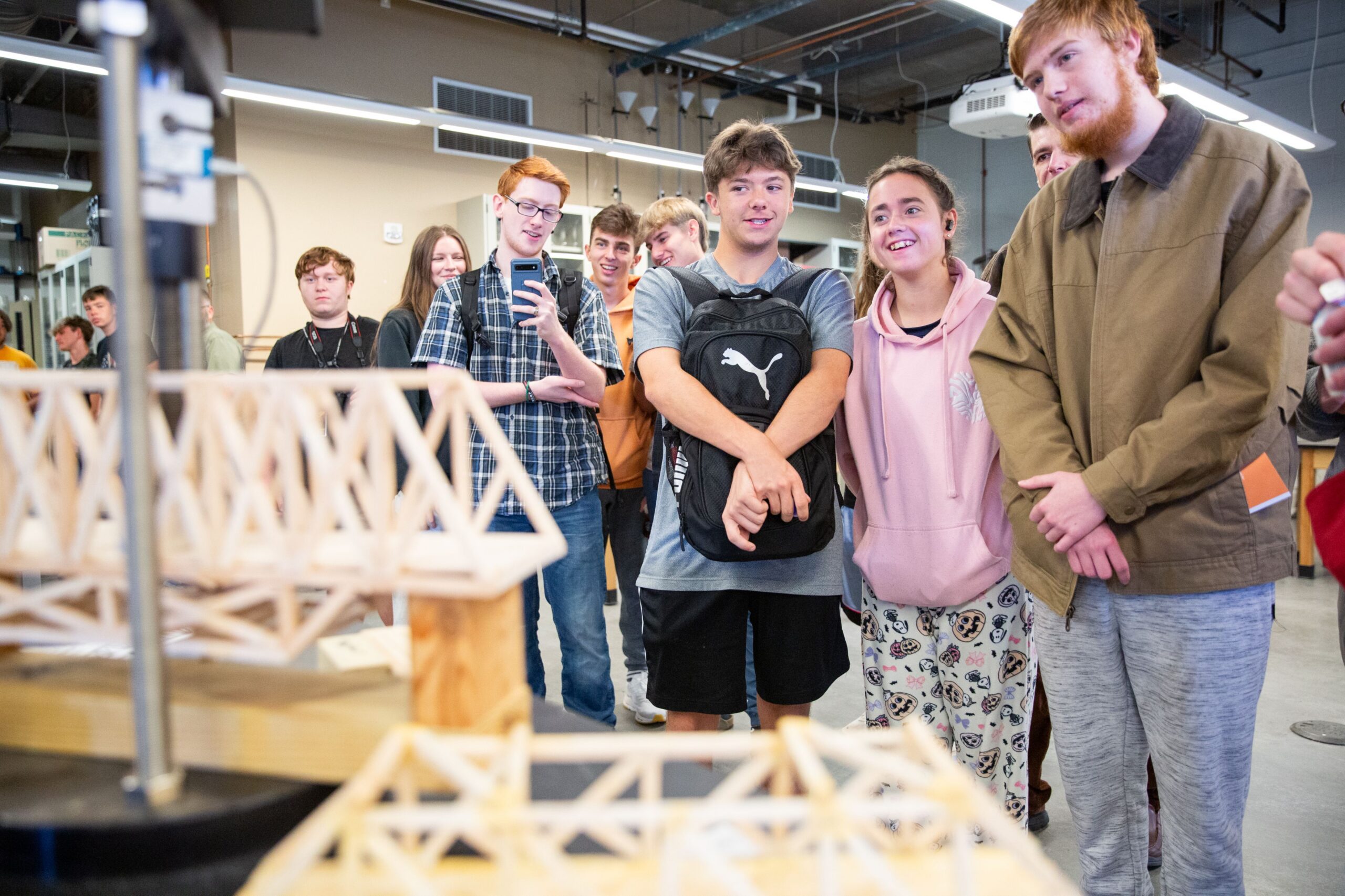 High school students observing a popsicle stick bridge
