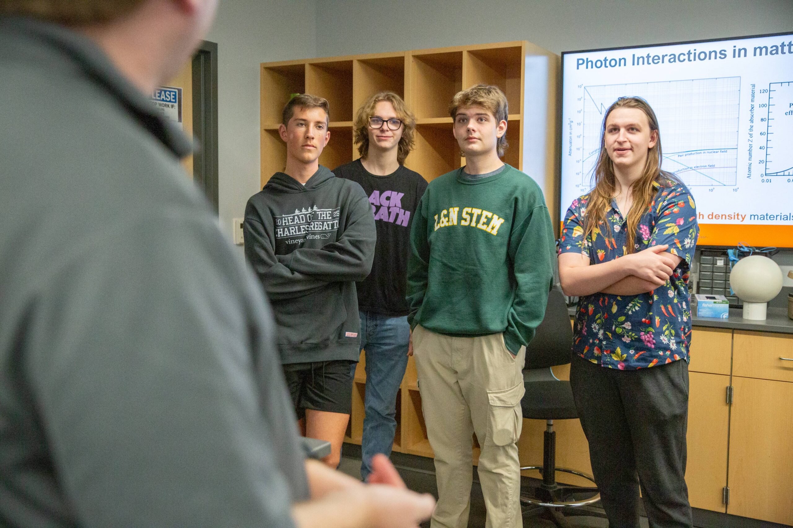 A faculty member talking to a group of four high school students while presenting