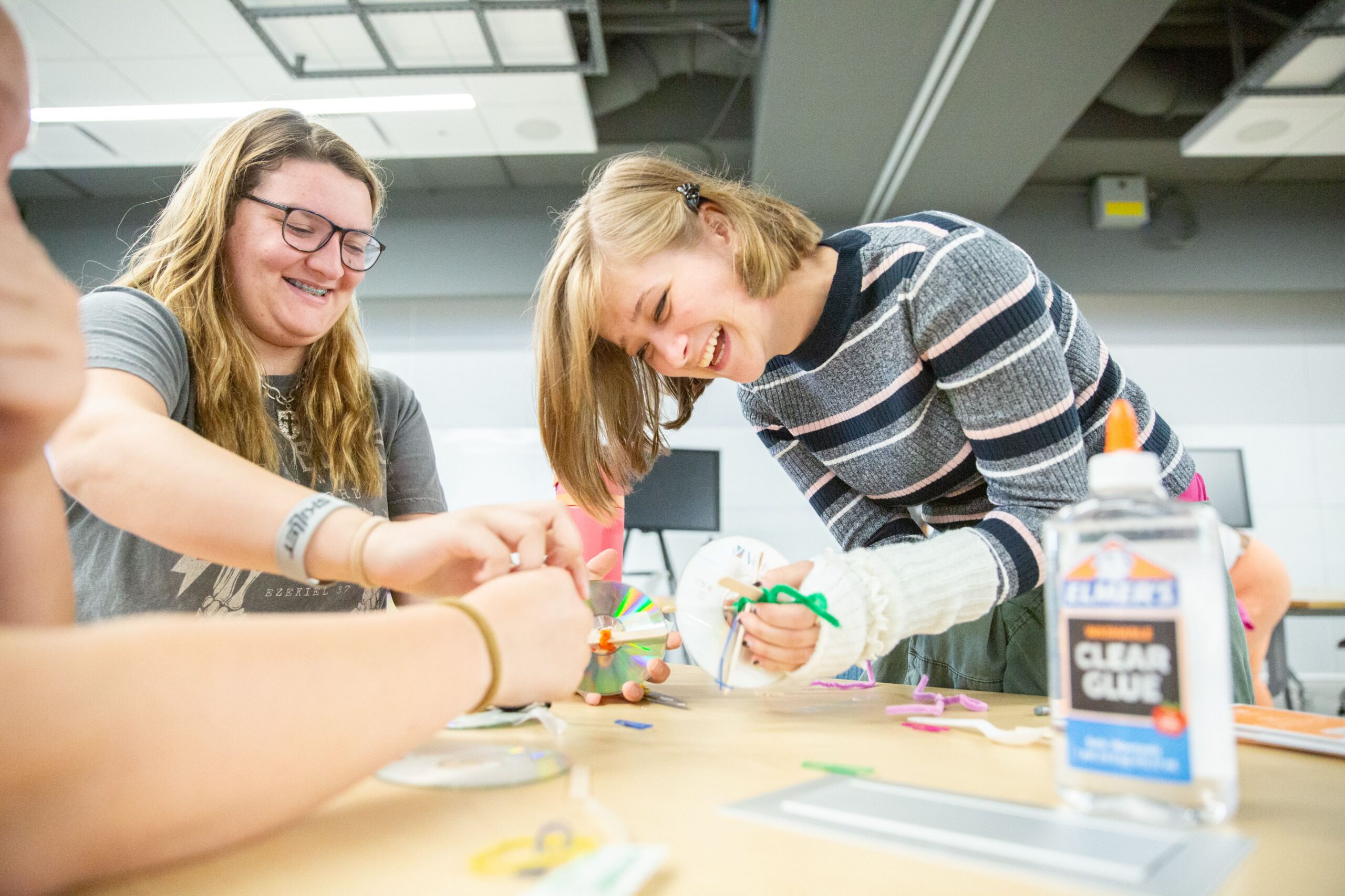 High school students laughing while putting together a prototyped car with CD wheels